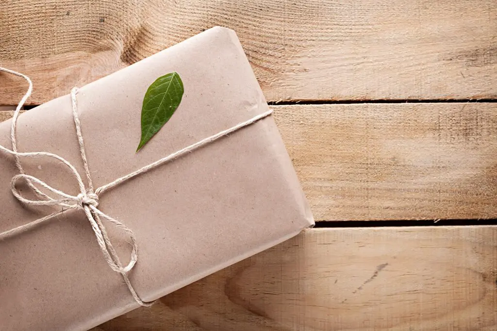 Gift box with a green leaf on a wooden background