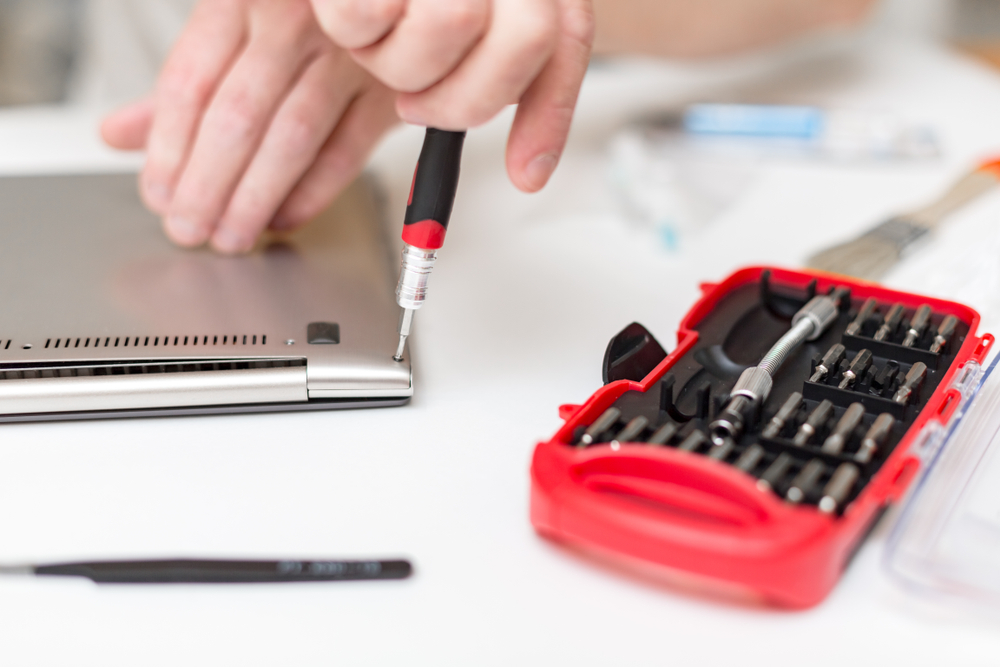 Toolkit with man's hands fixing a laptop